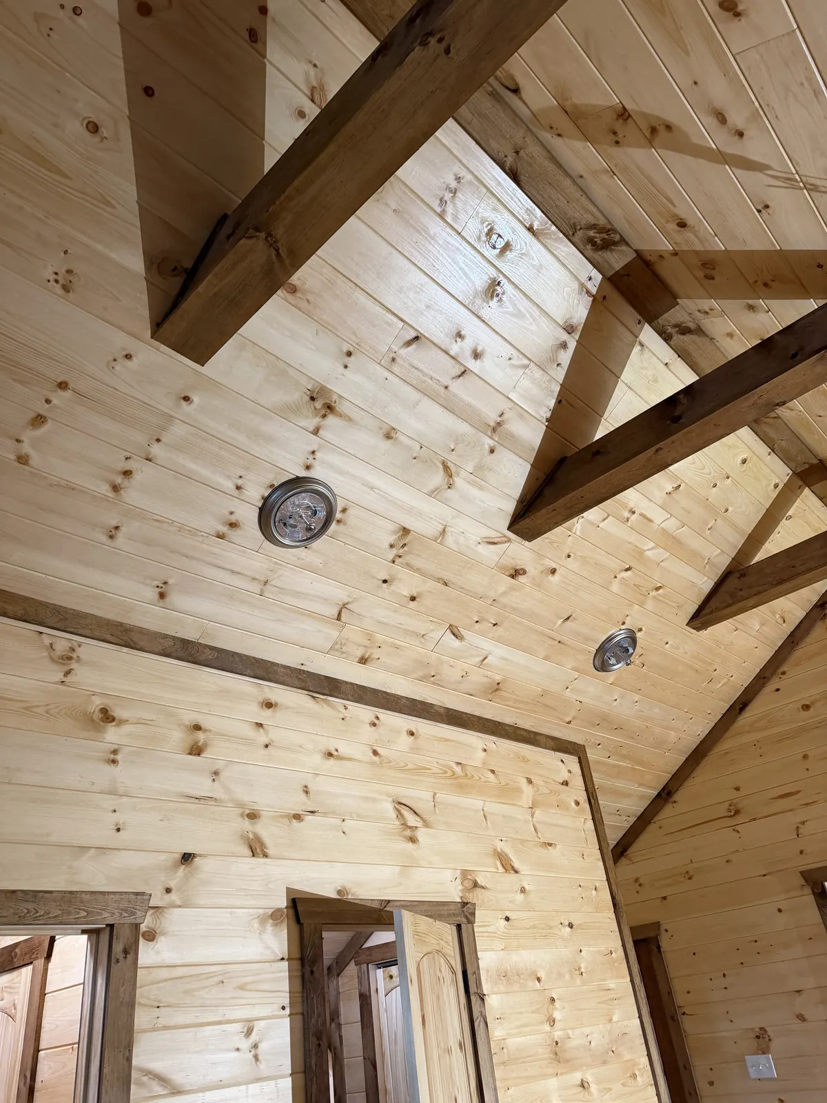Timber collar beams across a vaulted tongue-and-groove pine ceiling