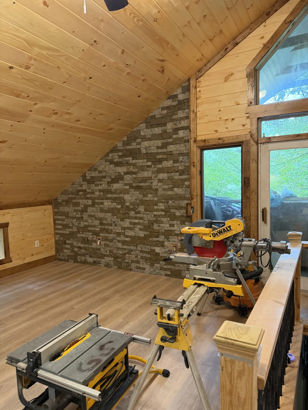 Stacked stone accent wall in a pine loft with saws set up for trim work