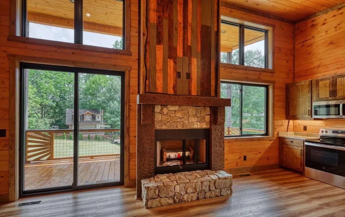 Second living area with a reclaimed wood and stone fireplace and an open kitchen