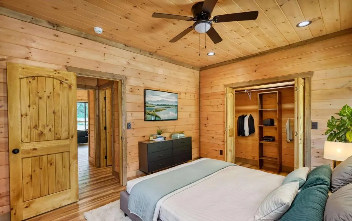 Bedroom with pine walls and knotty pine doors, shown virtually staged