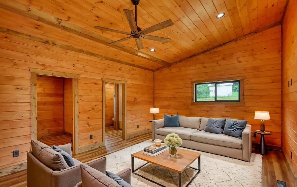 Den with a vaulted pine ceiling, shown virtually staged