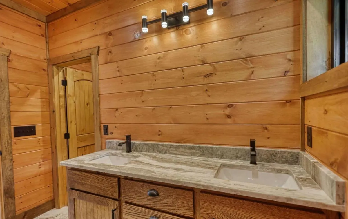 Double vanity with a stone top against pine walls
