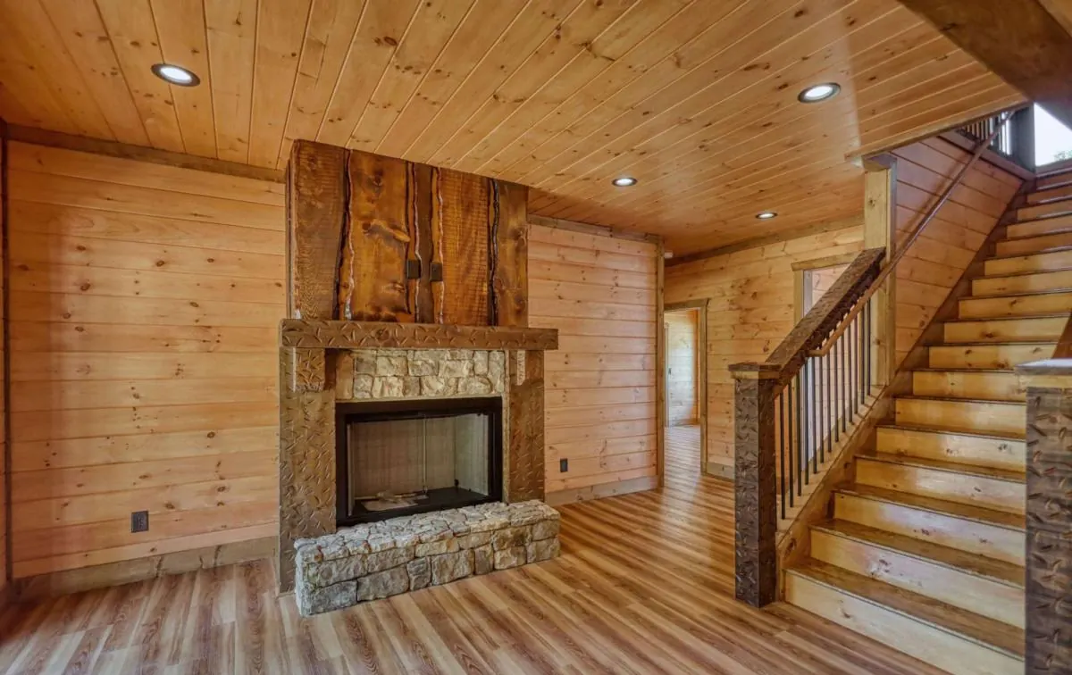 Stone fireplace with a rough-sawn wood surround beside the staircase