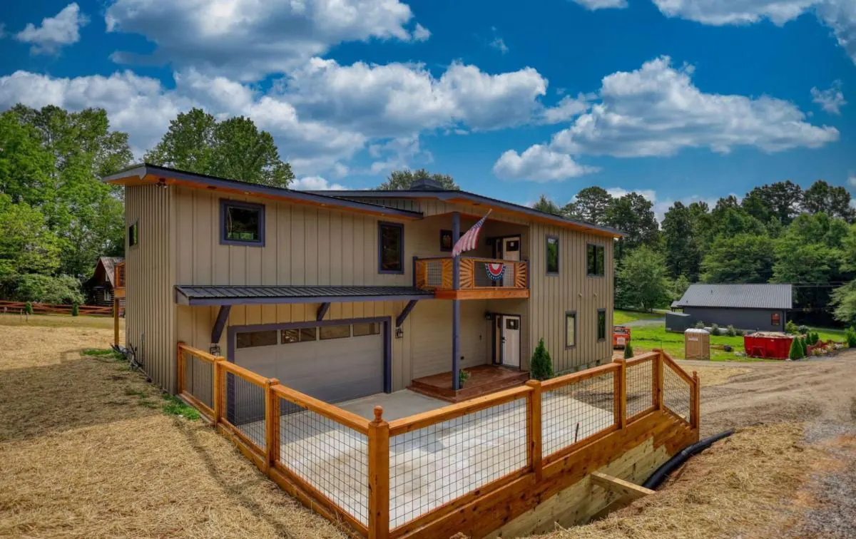 Corner of the house with the garage and a long deck with wire railing