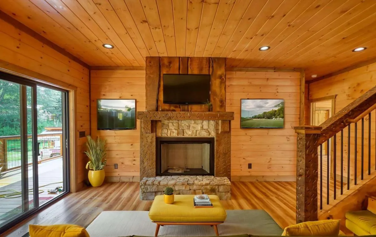 Living room with a stone fireplace, shown virtually staged with furniture