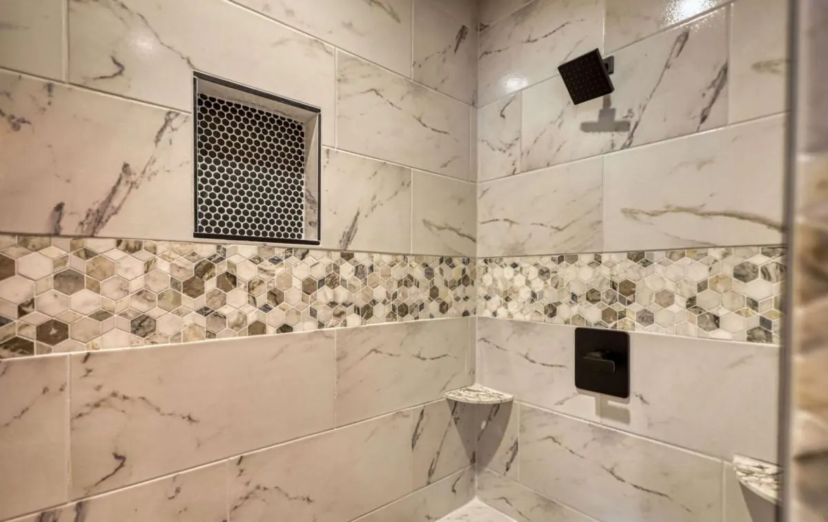 Tiled walk-in shower with a hexagon mosaic band and a niche