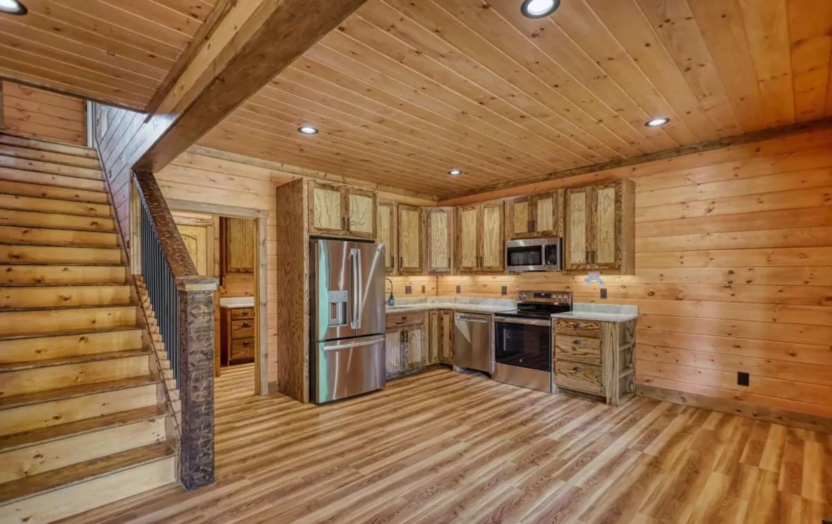 Staircase with metal balusters and rustic posts beside the kitchen