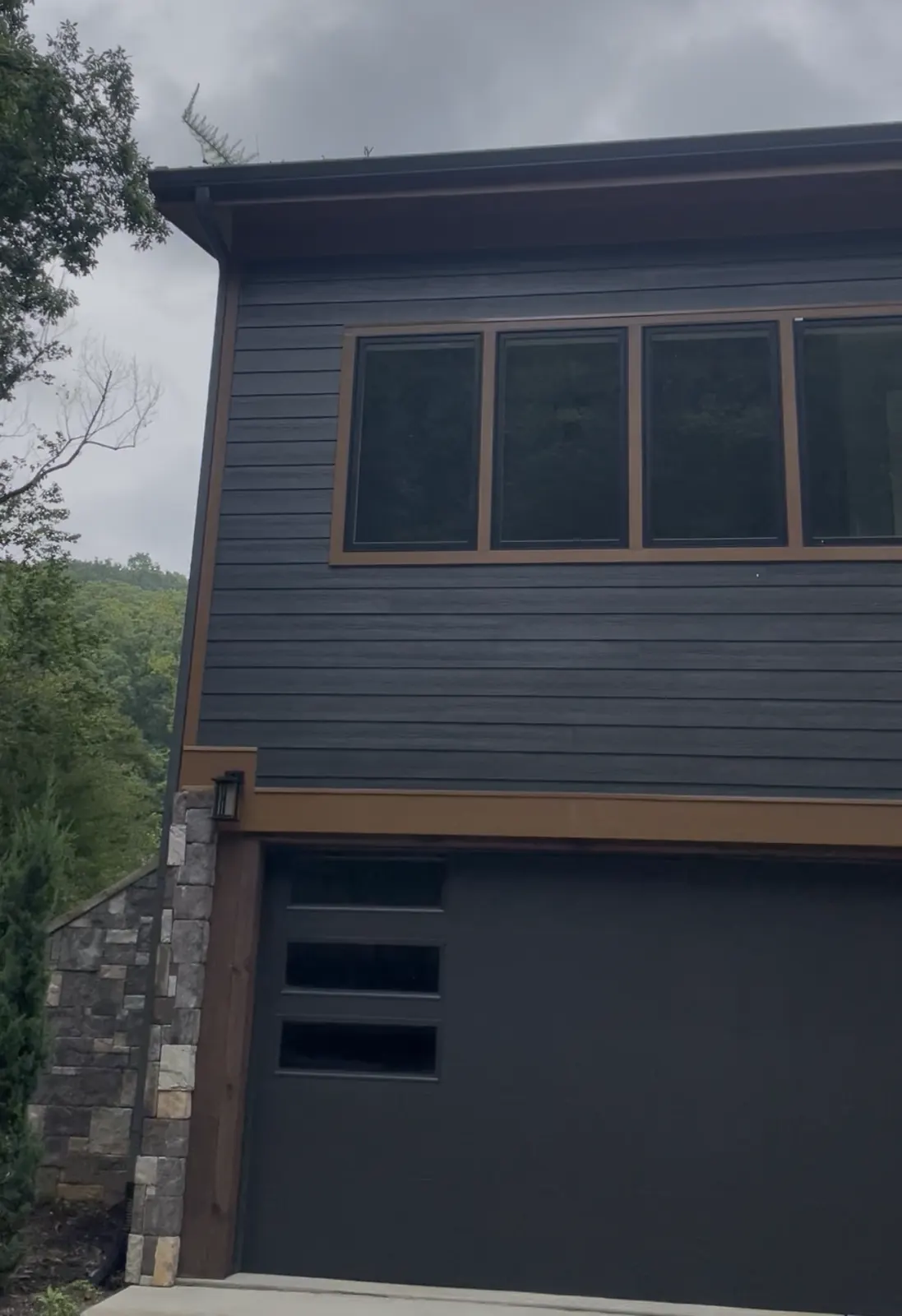 Dark gray new build with a modern garage door and a row of upper windows
