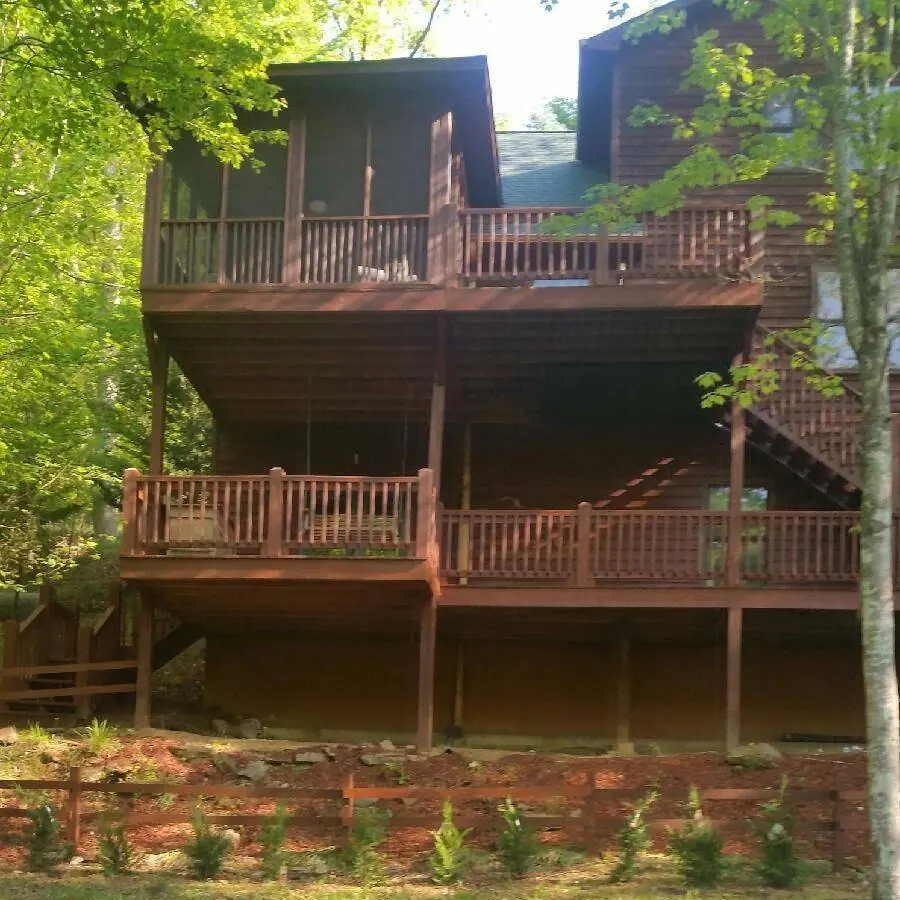 Three-level log home with stained decks and railings on a wooded hillside