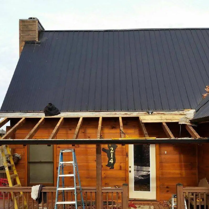 Log home with a dark metal roof and the porch roof framing opened up