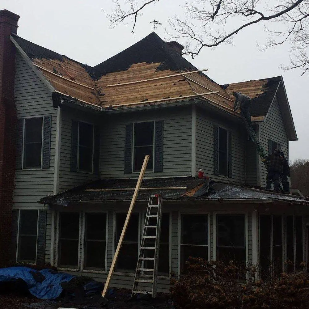Two-story house with the old roofing torn off down to the decking