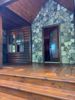 Covered entry with stacked stone wall and stained wood steps