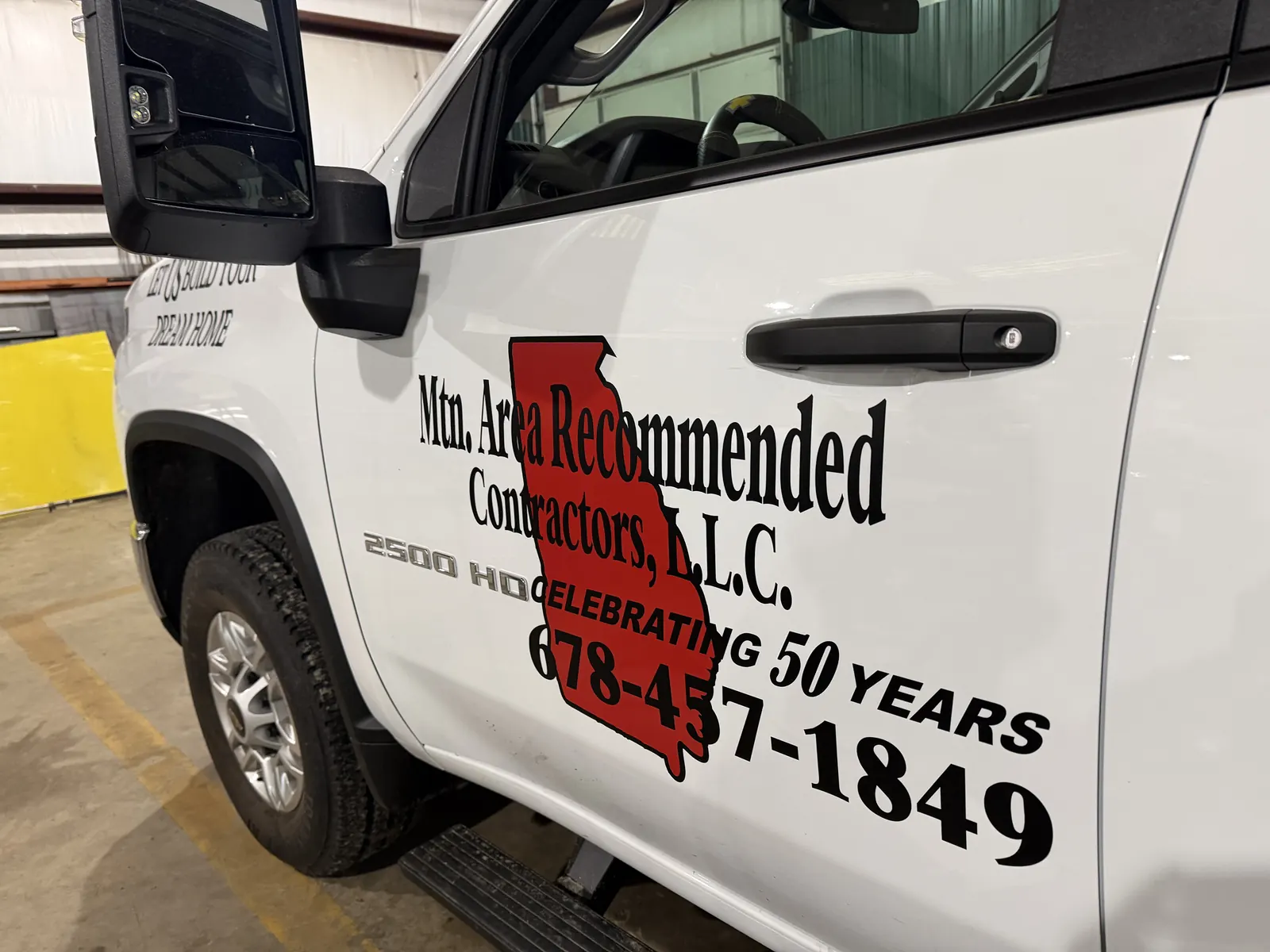 Truck door lettered Mtn. Area Recommended Contractors, LLC, celebrating 50 years, 678-457-1849, over a red outline of Georgia