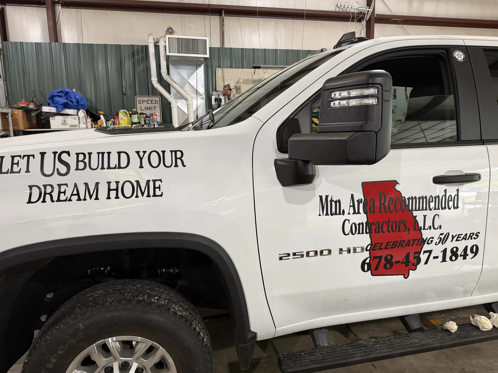 White company pickup lettered "Let us build your dream home" with the Mountain Area Recommended Contractors name and phone number