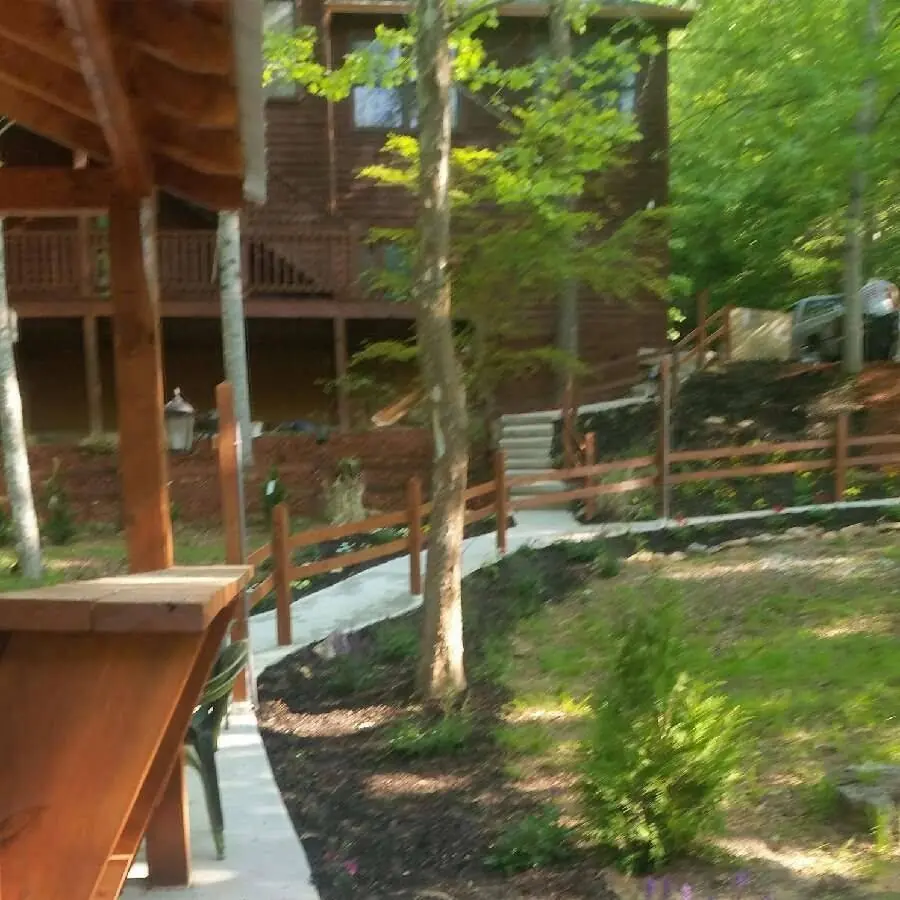 Concrete walkway and stained rail fence running below a log home deck